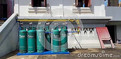 Group of new green gas tank install with value, yellow pipe or pipeline and white building or home background Editorial Stock Photo