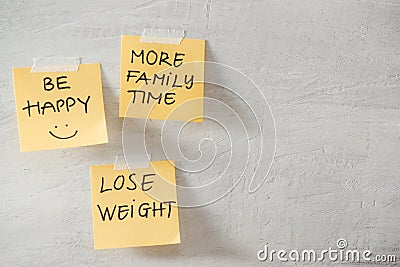 Group of New year Resolution Notes on yellow on wall written with message of more family time, lose weight and be happy Stock Photo