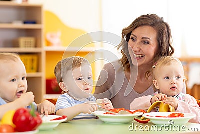 Group of nursery babies eating healthy food lunch break together Stock Photo