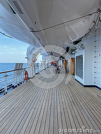 A group of passengers lounging in chairs under the life rafts on the deck of a cruise ship Editorial Stock Photo