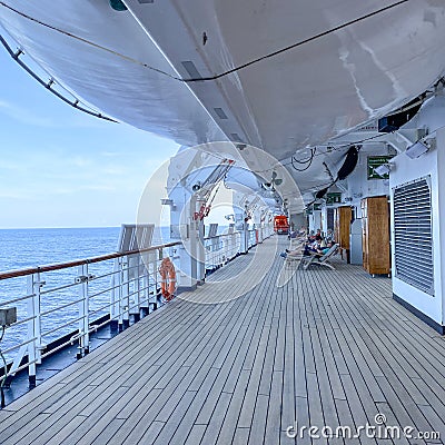 A group of passengers lounging in chairs under the life rafts on the deck of a cruise ship Editorial Stock Photo