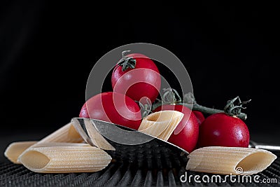 Group of penne macaroni pasta and tomatoes in a large chrome spoon Stock Photo