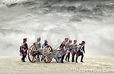 Group of people dressed as Napoleonic-era soldiers and marching in open land with a cannon Editorial Stock Photo