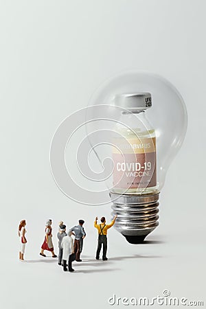 Group of people figurine standing against the Coronavirus COVID-19 vaccine in bulb light Stock Photo