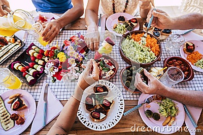 Group of people friends or family caucasian celebrate together and enjoy a table full of fresh and coloured healthy food - concept Stock Photo