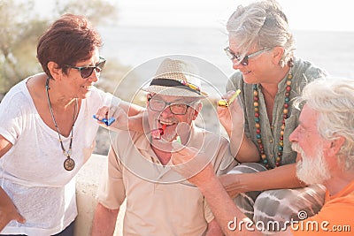 Group of people having fun together celebrating something happened - four seniors smiling and laughing at the beach Stock Photo