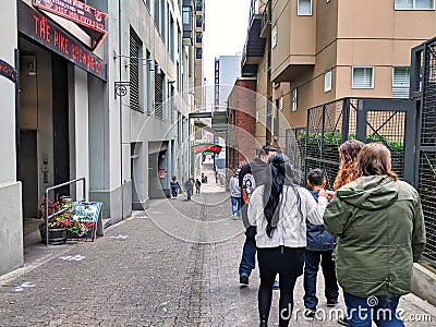 Group of people making their way down Post Alley past the gum wall in Pike Place Market Editorial Stock Photo