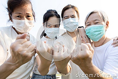 Group of people with medical mask to prevent infection from spreading of Covid-19,asian family raised a fists and prepare for the Stock Photo