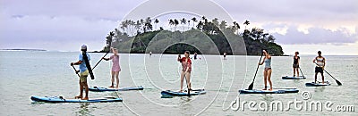 Group of people peddle boarding over Muri Lagoon at sunset in Ra Editorial Stock Photo