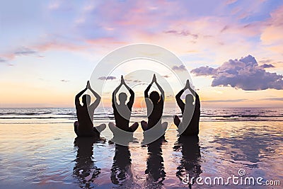 Group of people practicing meditation and yoga, beach, sunset, harmony Stock Photo