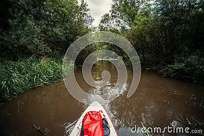 A group of people are rafting. A trip on a SAP board. A narrow river in the middle of the forest, an extreme route. bag with water Stock Photo