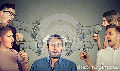 Group of people screaming in megaphones at scared guy Stock Photo