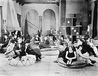 Group of people sitting on oversized cushions in a hall Stock Photo