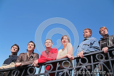 Group of people stand leaning on handrail Stock Photo