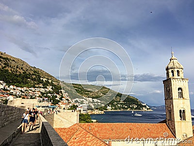 A group of people walking along the Walls of Dubrovnik with the Adriatic sea glistening in the background, in Dubrovnik, Croatia. Editorial Stock Photo