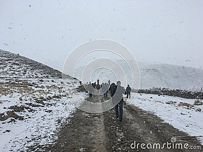 Group of people walking on dirt road in snow Editorial Stock Photo