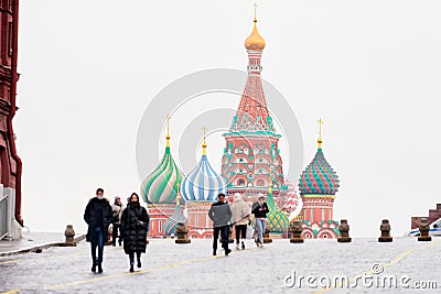 A group of people in warm clothes crosses Red Square against the background of St. Basil`s Cathedral. Selective focus Editorial Stock Photo
