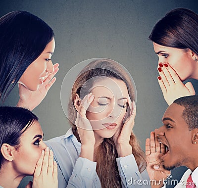 Group of people whispering gossip to a stressed woman suffering from headache Stock Photo