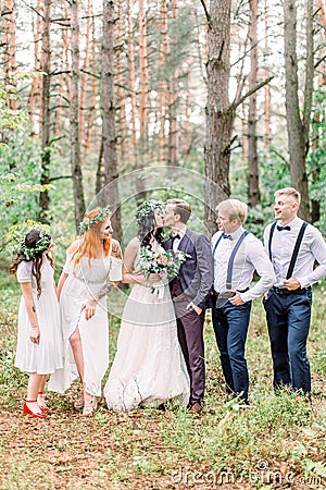 The group photo of the groom and his best men, the bride with the bridemaids at the background of the pine green forest Stock Photo