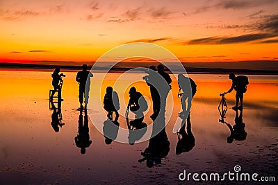 A group of photographers taking pictures in the salt lake. Human silhouettes and reflection Editorial Stock Photo