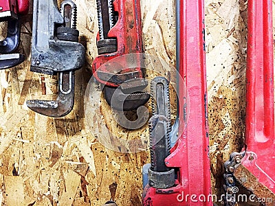 Group of pipe wrenches hanging on wooden wall. Stock Photo
