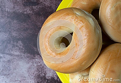 Group of plain bagels on a large yellow plate atop a red mottled countertop top view Stock Photo