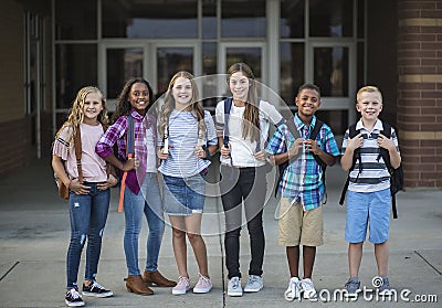 Group portrait of pre-adolescent school kids smiling in front of the school building Stock Photo