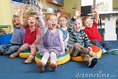 Group Of Pre School Children Answering Question In Classroom Stock Photo