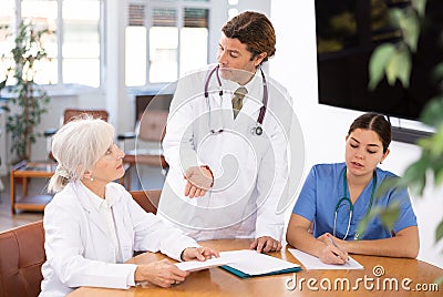 Group of professional doctors sitting at table and discussing diagnosis and treatment of patients during medical council Stock Photo