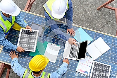 Group of professional engineering people wearing helmets and safety vests meeting with solar photovoltaic panels discussion for Stock Photo