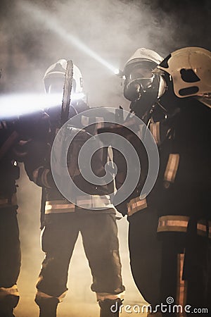 Group of professional firefighters wearing full equipment, oxygen masks, and emergency rescue tools, circular hydraulic and gas Stock Photo
