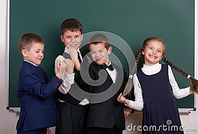 Group pupil as a gang, posing near blank chalkboard background, grimacing and emotions, dressed in classic black suit Stock Photo