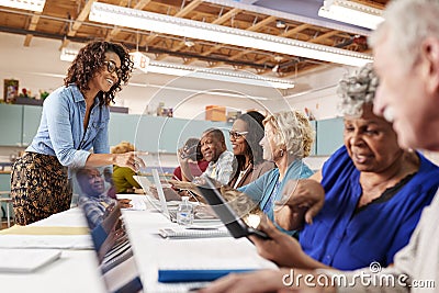 Group Of Retired Seniors Attending IT Class In Community Centre With Teacher Stock Photo