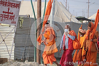 A group of Sadhus wearing orange attire walking on the pilgrim route to holy Ganges and Sangam. Editorial Stock Photo