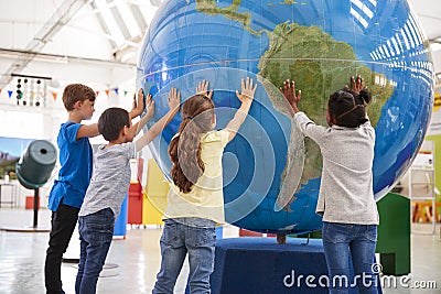 Group of school kids holding giant globe at a science centre Stock Photo