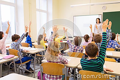 Group of school kids raising hands in classroom Stock Photo