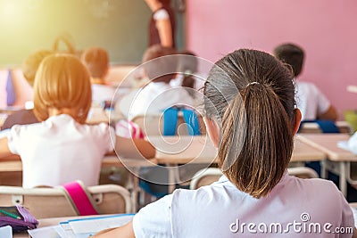 group of school kids sitting and listening to teacher in classroom from back Editorial Stock Photo
