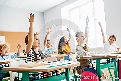 group of schoolchildren raising hands to answer question Stock Photo