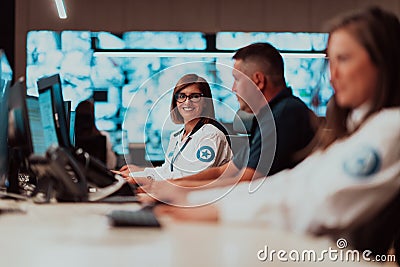 Group of Security data center operators working in a CCTV monitoring room looking on multiple monitors Officers Stock Photo