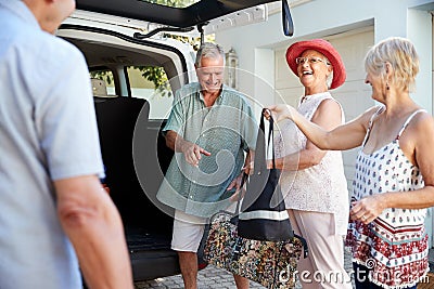 Group Of Senior Friends Loading Luggage Into Trunk Of Car About To Leave For Vacation Stock Photo
