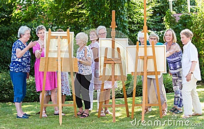 Group of senior ladies enjoying an art class outdoors in a park or garden as a therapeutic recreational activity at a care home. Stock Photo