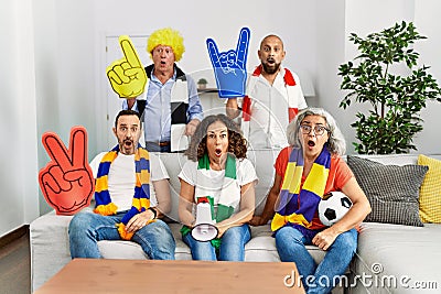 Group of senior people supporting soccer team at home scared and amazed with open mouth for surprise, disbelief face Stock Photo