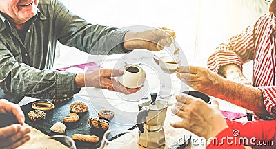 Group of senior people toasting italian style moka coffee after lunch - Mature happy friends eating biscuits and laughing together Stock Photo