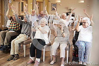 Group Of Seniors Enjoying Fitness Class In Retirement Home Stock Photo