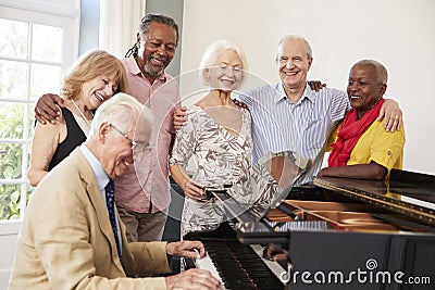 Group Of Seniors Standing By Piano And Singing Together Stock Photo