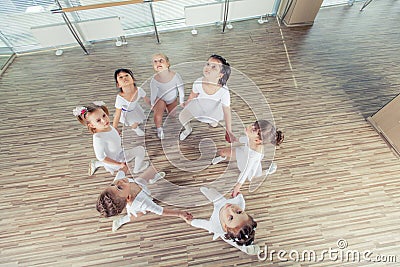 Group of seven little ballerinas sitting on the floor. They are good friend and amazing dance performers Stock Photo