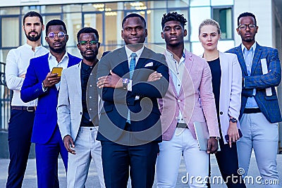 A group of seven successful business people men and woman in stylish suits standing and looking proudly outdoors Stock Photo