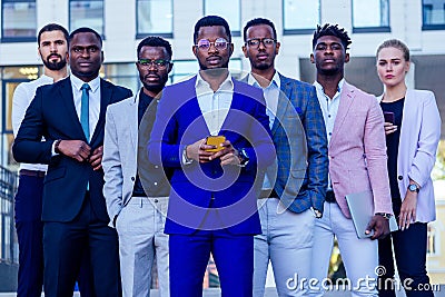 A group of seven successful business people men and woman in stylish suits standing and looking proudly outdoors Stock Photo