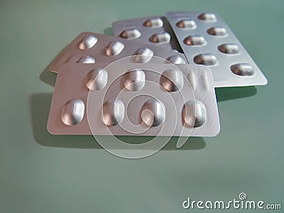 Group of Silver Blister Packs of Pills on Light Green Background Stock Photo