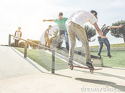 Group of skaters friends performing trick and skills in urban contest - Young men training with boards in skate park at sunset - Stock Photo
